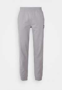 Lichtgrijze sportieve joggerbroek met elastische tailleband en boorden, voorzien van een klein zwart merkembleem op de rechterdij.