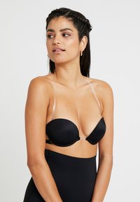 Sutiã acolchoado preto com alças transparentes e fecho de gancho; textura suave e copas contornadas projetadas para suporte e conforto.