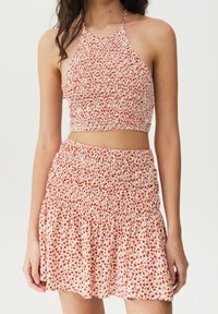 Roter und weißer Blumen-Crop-Top mit Halterneck-Design, kombiniert mit einem passenden Minirock mit elastischem Bund und Rüschensaum.