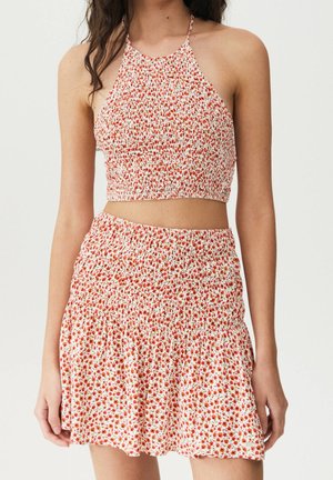 Roter und weißer Blumen-Crop-Top mit Halterneck-Design, kombiniert mit einem passenden Minirock mit elastischem Bund und Rüschensaum.