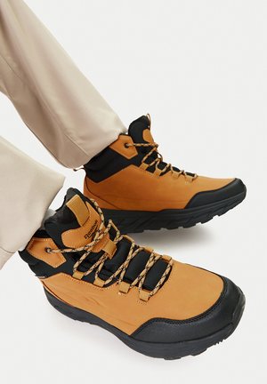 Brūnas un melnas pārgājienu zābaki ar teksturētu augšdaļu, polsterētu apkakli un pastiprinātu purngalu. Melnas mežģīnes ar rakstu. Gumijas zolīte.