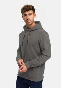 Szary sweatshirt z kapturem o prążkowanej strukturze, z kieszenią z przodu, regulowanymi sznurkami i akcentem z metką w pobliżu dekoltu.