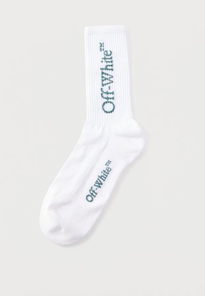 Λευκός ριμπ κάλτσα με πράσινο λογότυπο «Off-White™» τυπωμένο κάθετα στη μανσέτα και οριζόντια κοντά στην περιοχή των δαχτύλων.