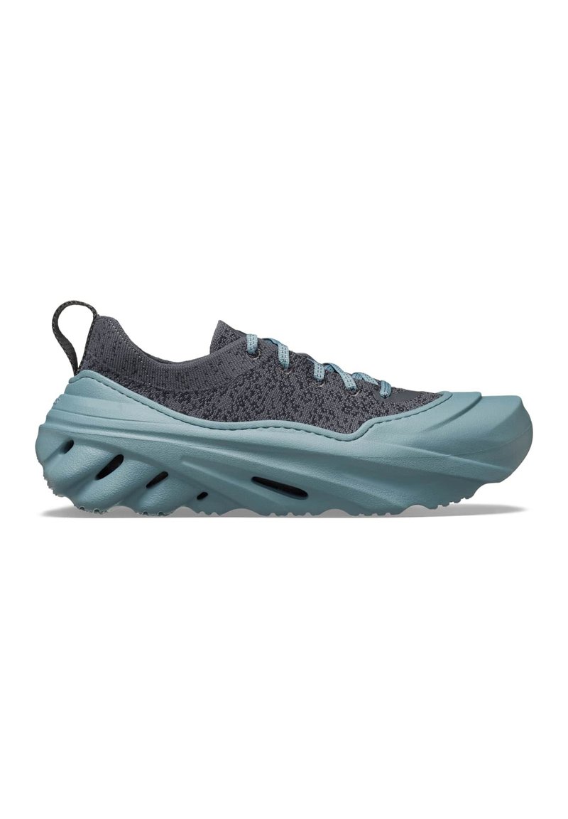 Herren-Laufschuh mit einer strukturierten dunkelgrauen Oberseite, teal-farbener Gummizwischensohle mit wellenartigen Rillen und flachen Schnürsenkeln zur Sicherung.
