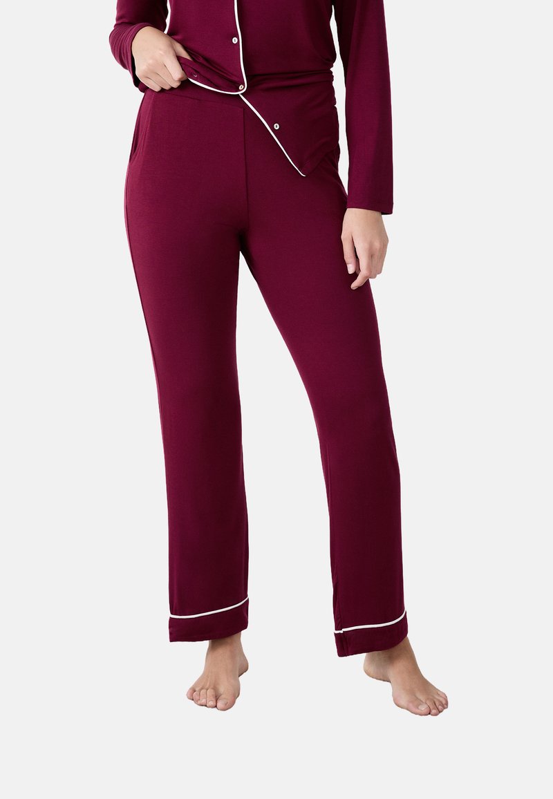 Bordeauxrode pyjamabroek van zacht materiaal, met zijzakken en witte bies aan de zoom, ontworpen voor comfort en bewegingsvrijheid.