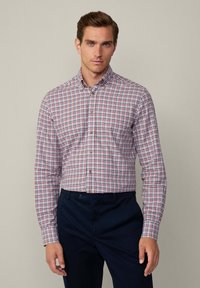 Camicia a quadri in tonalità rosso, bianco e blu; colletto con bottoni; maniche lunghe; materiale in cotone; presenta una vestibilità comoda e una sottile texture.