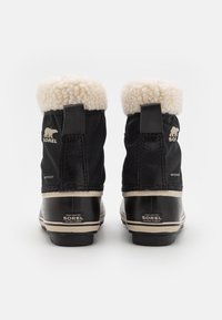 Svarte vanntette støvler med en myk, hvit kunstpelskrage, gummisåler og Sorel-merke på hælen og siden. Klassisk design.