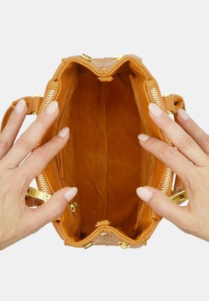 Sac à main en cuir tan avec un extérieur lisse, des accessoires en doré, une fermeture éclair et une doublure en tissu doux de couleur tan. Ouvert, montrant la structure intérieure.