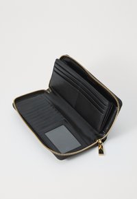 Portefeuille en cuir noir avec fermeture éclair dorée. Plusieurs emplacements pour cartes, une fenêtre pour ID transparente et un intérieur lisse. Design compact, fermeture éclair tout autour.