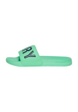 Chanclas verdes de goma con una tira ancha. La tira tiene letras en negrita en color negro. La suela es plana y texturizada para asegurar el agarre.