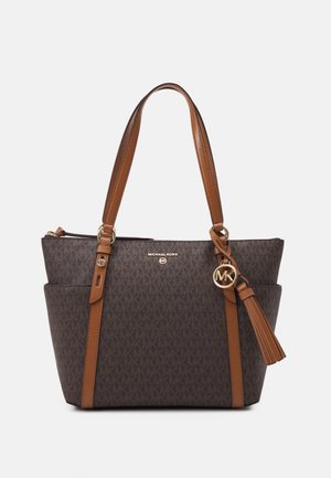 Bruine Michael Kors tote bag met monogrampatroon, beige leren handvatten, zijvakken en een tassel met gouden MK-logo hanger.