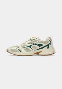 Λευκό αθλητικό παπούτσι με πράσινες λεπτομέρειες, επάνω μέρος από δίχτυ, επενδεδυμένη σόλα και εξωτερική σόλα από καουτσούκ τύπου γκαμ. Διαθέτει κορδόνια και ενισχυμένη ταμπελίτσα στη φτέρνα.