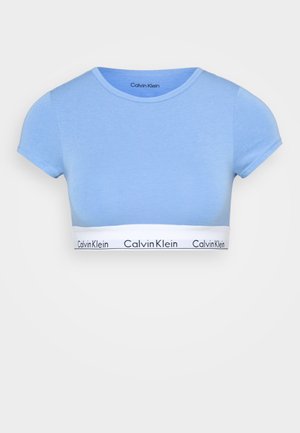 Lys blå crop top med korte ermer, laget av mykt stoff. Har en hvit midje med svart "Calvin Klein"-logo.