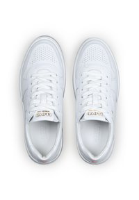 White leather sneakers with perforated toe detailing, flat laces, and branding on the tongue. Soft texture and rounded toe shape.