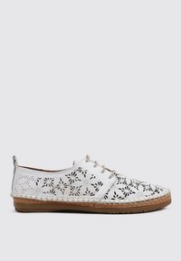 Zapatos blancos con cordones que presentan patrones florales recortados, hechos de cuero con una suela de yute cosida y una suela de goma texturizada marrón.