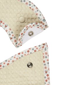 Blumenmusterstoff mit beigefarbenem Textilmaterial, ausgestattet mit Druckknöpfen; hat eine weiche Kante mit kontrastierendem Besatz und eine glatte Unterseite.
