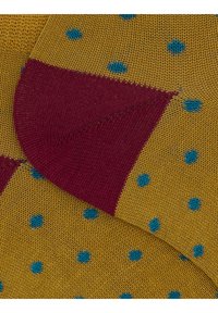 Gelbe Socken mit blauen نقاط و كرة قدم برای سهته وان ابهر فبریچ. Strukturiertes Strickmaterial. Unregelmäßiges Muster über die Oberfläche.