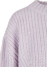 Maglione lavorato a maglia in morbido lavanda con un motivo a punto testurizzato e un collo rotondo a coste. La vista ravvicinata mostra il filato spesso e la vestibilità ampia.