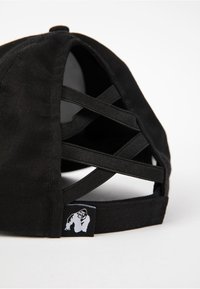 Black baseball cap featuring a crisscross strap design at the back, made of fabric with a small gorilla logo tag on the side.
