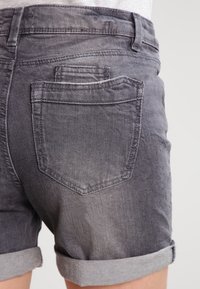 Haaleat mustat farkkushortsit, joissa on käännetty helma. Takana on kaksi taskua, joissa on korostettu ompelu ja hienovarainen tekstuuri.