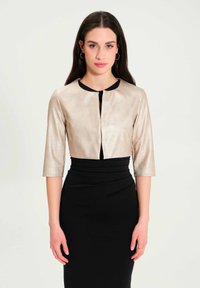 Metallic gold cropped jacket with a round neckline and three-quarter sleeves, paired with a form-fitting black skirt. Smooth texture, minimal design.