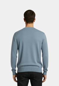 Maglione azzurro chiaro lavorato a maglia con scollo rotondo, polsini e orlo a coste. Tessuto dalla texture liscia, design aderente e tessuto di peso medio.