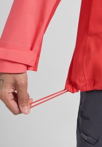 Veste rouge légère avec manches longues, ourlet élastiqué et cordons de serrage. Tissu doux et détail de couture contrastante.