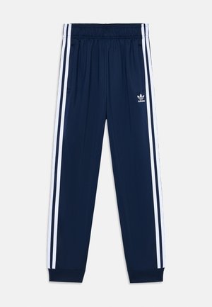 Marineblå Adidas træningsbukser med elastisk talje, hvide tredobbelte striber på siderne, ribstrikkede manchetter og Adidas-logo på venstre lår.