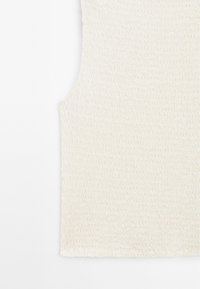 Teksturowany próbek tkaniny w kolorze off-white z falistym wzorem, prezentujący miękki materiał i gładkie wykończenie. Brak widocznych szwów lub elementów metalowych.