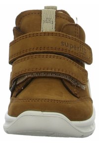 Scarpa per bambini in suede marrone con due cinturini in Velcro, colletto imbottito e suola in gomma bianca. Logo "Superfit" impresso sul cinturino.