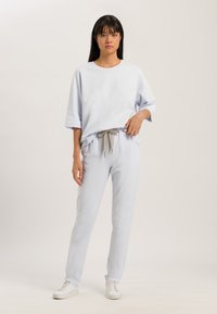 Ljusblå loungewear-set i mjukt tyg, med en lös passform på kortärmad topp och avsmalnande byxor med dragsko i midjan. Sneakers fulländar looken.