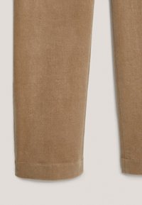 Bruna kordbyxor med en mjuk textur, med rak passform och uppvikt fåll vid anklarna, som visar ett vertikalt ribbat mönster.