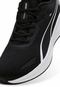 Scarpa da corsa nera con una tomaia in mesh, lacci neri e una suola intermedia bianca con accenti sottili. Include una superficie testurizzata e dettagli di branding.