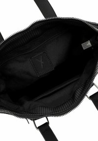 Black handbag with zip closure, smooth fabric interior, internal pocket, logo tag, and flat straps; features a ribbed edge on the opening.