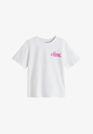 Biały t-shirt z krótkim rękawem i okrągłym dekoltem z różowym napisem „Seoul STATE OF MIND” na lewej piersi.