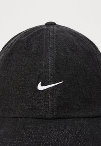 Casquette en denim noir avec un visière courbée, logo Nike brodé en blanc à l'avant et deux trous d'aération sur les côtés.