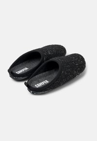 Pantofole nere con texture, upper in maglia, solette imbottite e suola in gomma con motivo. Presentano un logo sulla fodera interna.