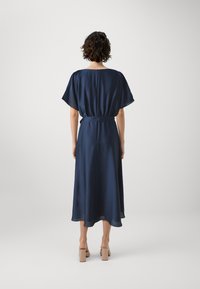 Robe midi bleu marine en tissu lisse, dotée de manches courtes, d'une ceinture à la taille et d'un ourlet fluide avec une finition douce et transparente.