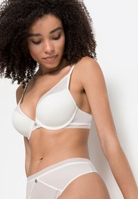 Wit lingerieset met een geribbelde structuur, gladde cups en verstelbare bandjes. De slipjes hebben bijpassende strepen en een decoratieve accent.