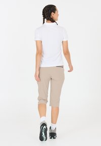Let lette, hvide polo skjorte, beige cropped bukser og sorte vandrestøvler med mint accenter. Outfittet er designet til udendørs aktiviteter.