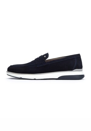 Chaussure slip-on en suede bleu marine avec une semelle en caoutchouc blanche et noire, présentant des coutures décoratives et un accent tissé sur l'empeigne.
