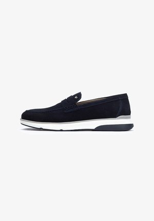 Chaussure slip-on en suede bleu marine avec une semelle en caoutchouc blanche et noire, présentant des coutures décoratives et un accent tissé sur l'empeigne.