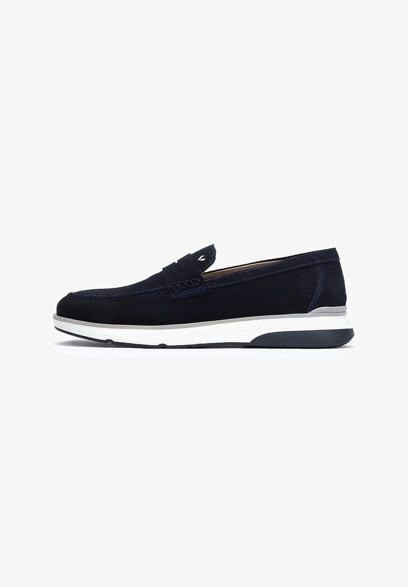 Chaussure slip-on en suede bleu marine avec une semelle en caoutchouc blanche et noire, présentant des coutures décoratives et un accent tissé sur l'empeigne.