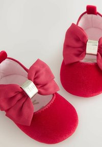 Rote Cord-Ballerinas mit großen, gerippten Schleifen an der Vorderseite, einschließlich eines Silber-Hardware-Elements und einem weichen Innenfutter.