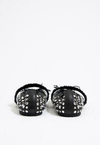 Zapatos planos negros con embellishments de tachuelas, con punta redonda, textura fruncida y tira de tela suave.