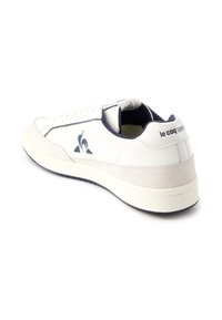 Vitaid sportskor i vitt med marinblå detaljer, tillverkade av mocka och syntetiska material, med snörning, logotyp på sidan och en texturerad gummisula.