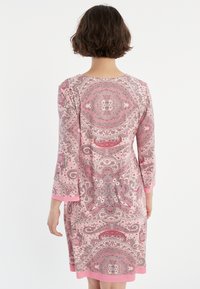 Rosa Paisley-muster Kleid mit Dreiviertelärmlen, einfachem Rundhalsausschnitt und kontrastierendem pinkfarbenem Besatz an den Ärmeln und dem Saum.