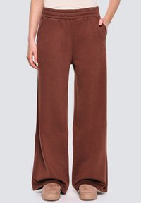 Brązowe dresy o luźnym kroju, z elastycznym pasem i miękkiego materiału. Posiadają kieszenie boczne i subtelny detal z logo w okolicy pasa.
