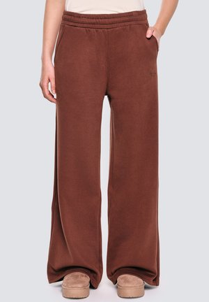 Bruine trainingsbroek met een relaxte pasvorm, elastische tailleband en zachte stof. Bevat zijzakken en een subtiele logodetail nabij de taille.