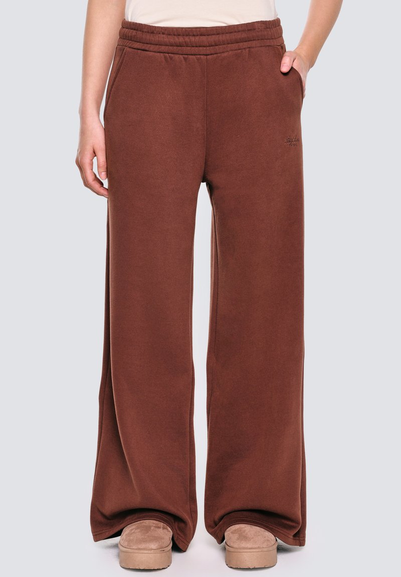 Brązowe dresy o luźnym kroju, z elastycznym pasem i miękkiego materiału. Posiadają kieszenie boczne i subtelny detal z logo w okolicy pasa.